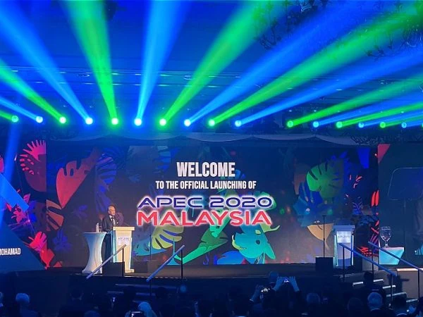 A large stage featuring Tun Dr Mahathir, Malaysia's 7th Prime Minister speaking, accompanied by a prominent screen, at the APEC 2020 Malaysia launch event organized by Moonman Events sdn bhd