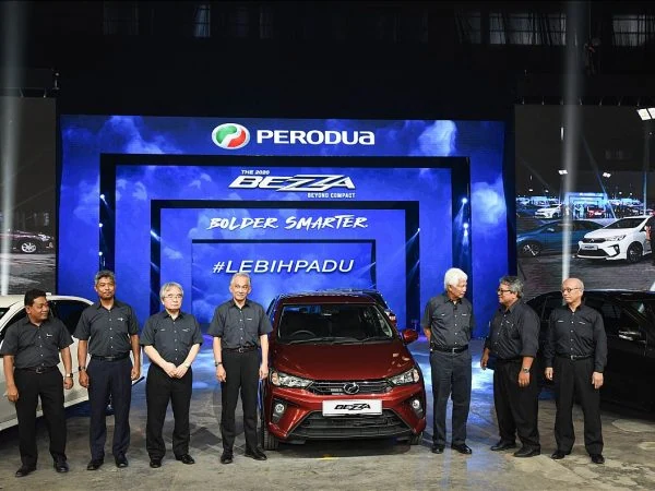 Top management of Perodua proudly pose with their new Perodua Bezza cars at the launch event organized by Moonman Events sdn bhd, showcasing excitement and celebration.