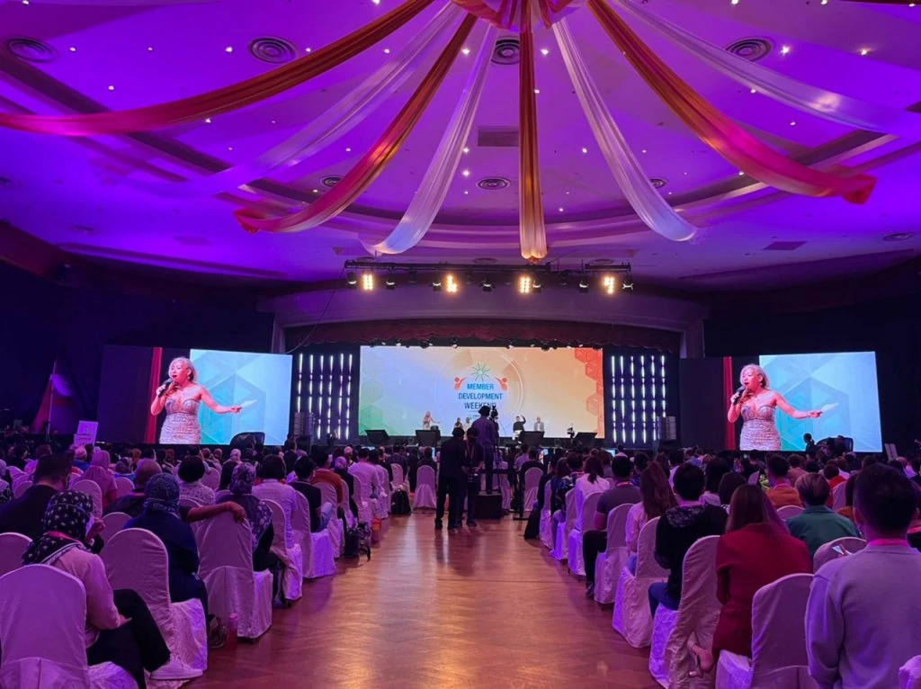 Attendees in a large room, seated in chairs, engaging with a large screen at the Herbalife Nutrition Member Development Weekend 2022 organized by Moonman Events sdn bhd