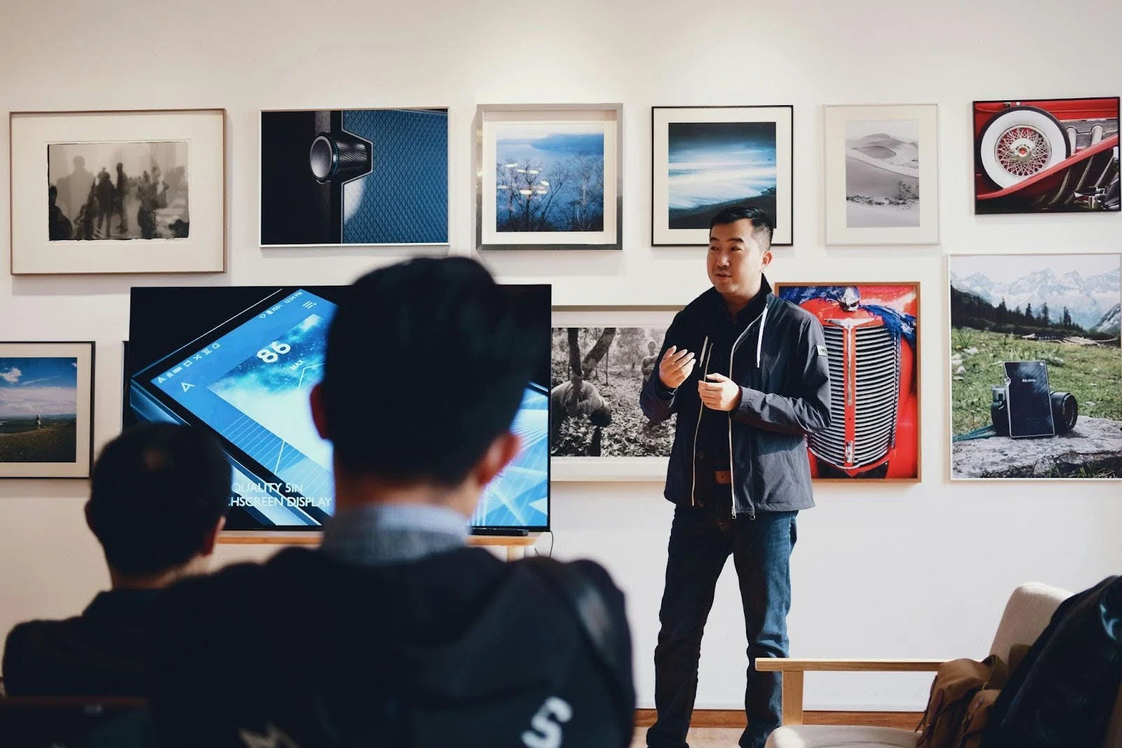 a man presenting in front of a group of people in a gallery