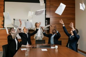 employees in a meeting room throwing files to the air as they don't have to worry about planning the event and leave it to Moonman Events, the top event organizer company in malaysia