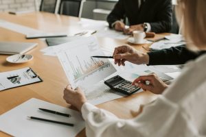 a shot of 3 employees sitting at a table in a meeting room reviewing a graph while calculating the budget for the event which will be planned and organized by Moonman Events, one of the top event companies in malaysia